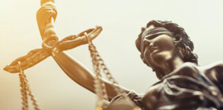 The Hidden Risks of Failing to Comply with GMP Close up of metal scales of justice, lady justice with golden lighting