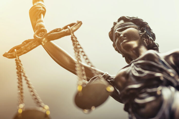 Close up of metal scales of justice, lady justice with golden lighting