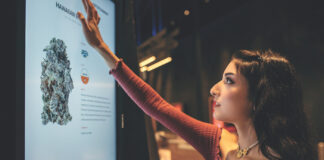 New Study Reveals Female Cannabis Consumer Motivations for 2025 Woman with red shirt and brown hair reaching up to touch a Dispensary Interactive Menu