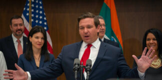 Politicians, Voters, Pollsters Disagree about Adult Use in Florida Florida Governor Ron DeSantis speaking in front of microphones behind a podium wearing a dark suit, white shirt, and red tie