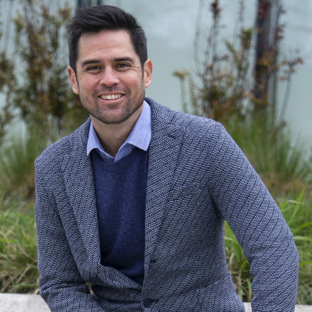 Randy Reed headshot, man with dark hard smiling in professional sport coat, sweater, and shirt