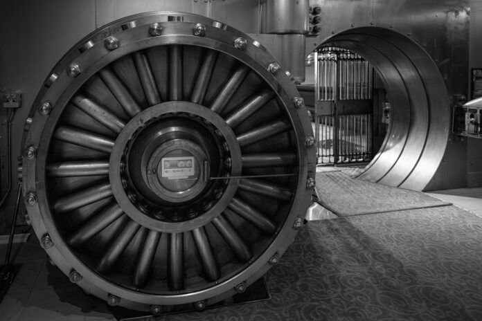 large bank vault door open with view into vault room shot in black and white