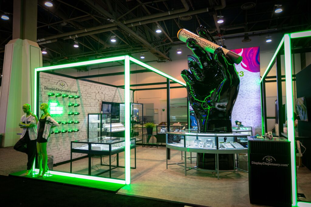 Display Dispensary booth at MJBizCon 2024 featuring a striking black hand sculpture and illuminated green accents.