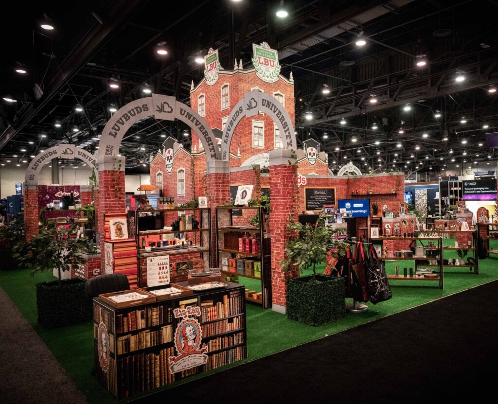 LuvBuds University-themed booth at MJBizCon 2024 featuring brick architecture and a variety of cannabis accessories on display.