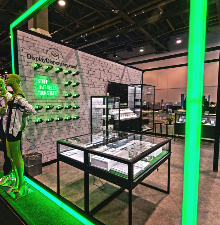 Glass product display cases framed by neon green lights, showcasing innovative retail merchandising solutions.