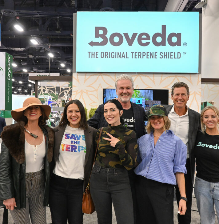 Boveda team posing at their MJBizCon 2024 booth, highlighting the Original Terpene Shield and cannabis storage solutions.