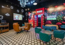 Inside Planet 13’s Dazed Consumption Lounge The interior of Dazed Consumption Lounge at Planet 13 Las Vegas, featuring futuristic neon wall designs, plush seating, and a vibrant mural with a surreal forest scene.