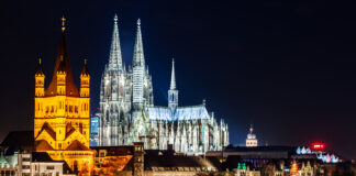 How International Cultivators Can Tap into Germany’s Cannabis Market Cologne Cathedral and Great St. Martin Church illuminated at night, symbolizing Germany’s growth.