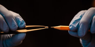 Revolutionizing Vape Tech: Greentank’s Quantum Innovation Close-up of Greentank’s Quantum Chip held by tweezers next to a pencil tip, highlighting the micro-scale size and precision engineering.