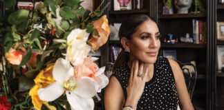 Marie Saloum Marie Saloum seated beside a vibrant floral arrangement, wearing elegant jewelry and a black polka-dot dress, inside her office space featured in Executive Insight by Macey Wolfer.