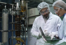 The Tariff Effect: What Cannabis Processors Need to Know Two scientists in a cannabis extraction lab reviewing equipment data, emphasizing American-made system compliance and quality standards.