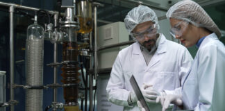 The Tariff Effect: What Cannabis Processors Need to Know Two scientists in a cannabis extraction lab reviewing equipment data, emphasizing American-made system compliance and quality standards.