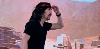 ‘High Times’ Magazine Resurrected in $3.5M Deal Josh Kesselman peering into the future while standing in front of a desert-themed digital backdrop, wearing a black shirt, bandana, and RAW belt buckle