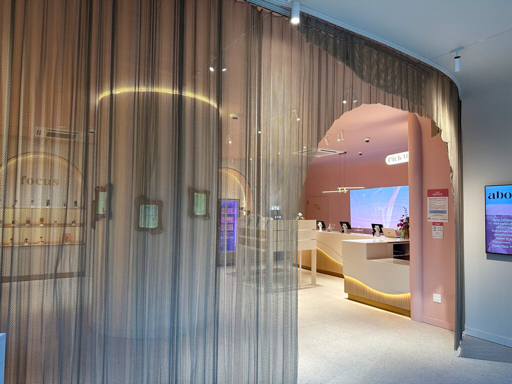 Mesh curtain installation providing privacy and ambiance inside Alta Dispensary, with illuminated arches visible beyond.