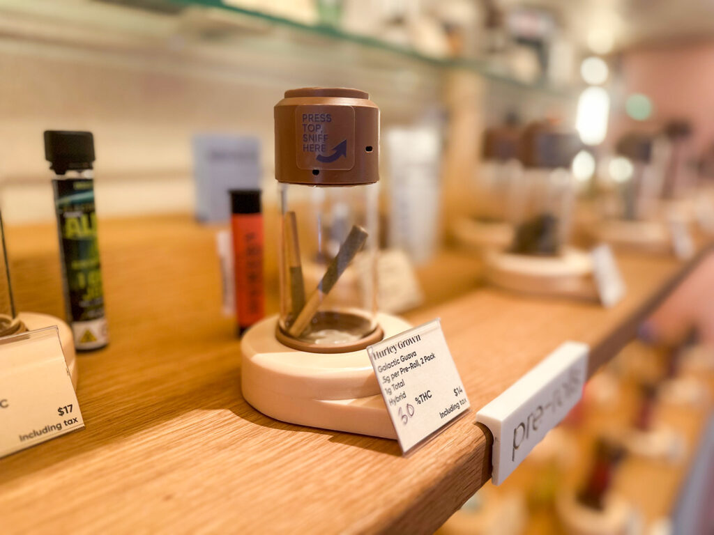 Close-up of interactive cannabis display jar labeled “Press to Sniff,” showcasing a pre-roll at Alta.