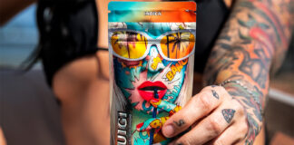 Premium Cannabis Meets Science and Style in Luigi Oil’s Flavor-Driven Lineup A tattooed woman in a black bikini holding a colorful Luigi Oil vape pouch featuring comic-style artwork and the word "Indica."