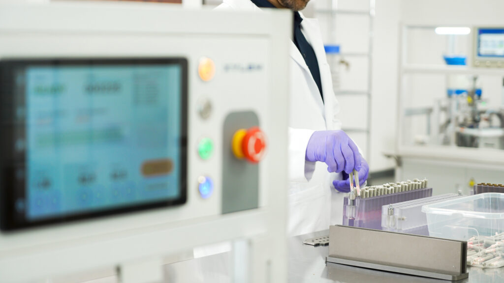 Lab technician wearing purple gloves loading cannabis pre-rolls into Xylem Robotics Y2 infusion machine.