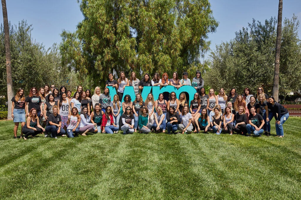 Group of WeedMaps employees in the cannabis industry posing together outdoors in front of branded company signage.