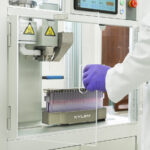 Engineering the Future of Infused Pre-Rolls with Xylem’s Y2 System Close-up of Xylem Robotics Y2 pre-roll infusion system in a cannabis lab, showing precision needle injector and tray of pre-rolls.