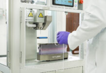 Engineering the Future of Infused Pre-Rolls with Xylem’s Y2 System Close-up of Xylem Robotics Y2 pre-roll infusion system in a cannabis lab, showing precision needle injector and tray of pre-rolls.