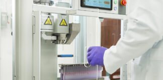 Engineering the Future of Infused Pre-Rolls with Xylem’s Y2 System Close-up of Xylem Robotics Y2 pre-roll infusion system in a cannabis lab, showing precision needle injector and tray of pre-rolls.