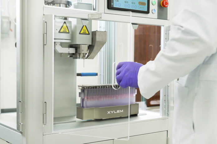 Close-up of Xylem Robotics Y2 pre-roll infusion system in a cannabis lab, showing precision needle injector and tray of pre-rolls.