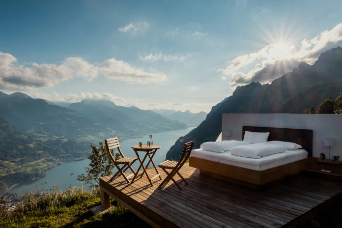 Scenic outdoor bedroom overlooking mountain lake at sunrise, symbolizing natural and holistic sleep environments inspired by wellness practices.