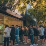 Dispensary Marketing in 2025: Google, AI, and Local Search Customers line up outside a modern cannabis dispensary in a bustling urban area, highlighting foot traffic and tourist interest.