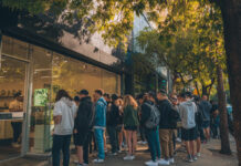 Dispensary Marketing in 2025: Google, AI, and Local Search Customers line up outside a modern cannabis dispensary in a bustling urban area, highlighting foot traffic and tourist interest.