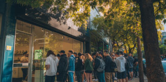 Dispensary Marketing in 2025: Google, AI, and Local Search Customers line up outside a modern cannabis dispensary in a bustling urban area, highlighting foot traffic and tourist interest.