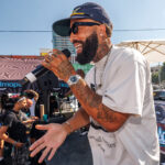 Weedmaps Hosts Star-Studded Kickback Event with DJ Mustard and Larry June Performer with microphone engaging the crowd during a live set at Weedmaps Kickback LA, with Weedmaps branding and DJ booth in background.