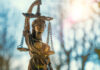 DoJ Shift: Stricter Marijuana Enforcement on Federal Lands lClose-up of a Lady Justice statue with sunlight flaring behind it, symbolizing federal law and policy.