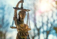DoJ Shift: Stricter Marijuana Enforcement on Federal Lands lClose-up of a Lady Justice statue with sunlight flaring behind it, symbolizing federal law and policy.