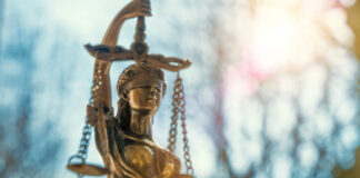 DoJ Shift: Stricter Marijuana Enforcement on Federal Lands lClose-up of a Lady Justice statue with sunlight flaring behind it, symbolizing federal law and policy.