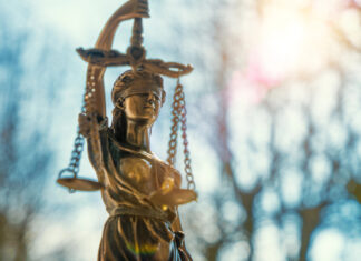 DoJ Shift: Stricter Marijuana Enforcement on Federal Lands lClose-up of a Lady Justice statue with sunlight flaring behind it, symbolizing federal law and policy.