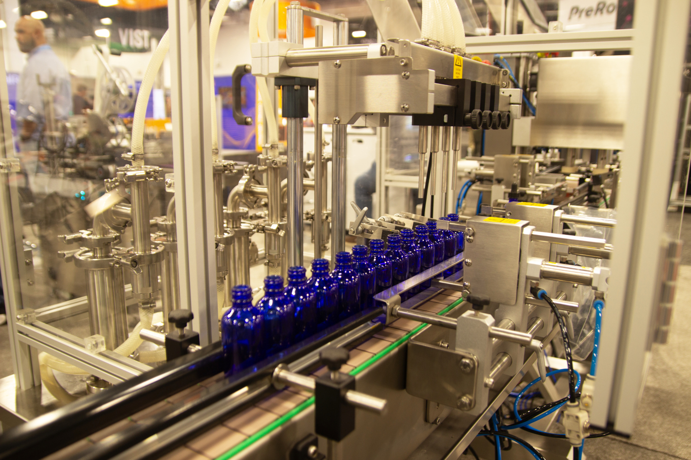 Pack Leader USA automated cannabis oil filling machine dispensing into blue glass bottles at MJBizCon 2025.