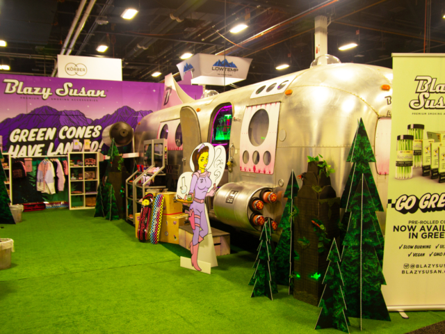 Blazy Susan&rsquo;s Airstream-themed booth at MJBizCon 2025 featuring pre-rolled green cones and accessories.