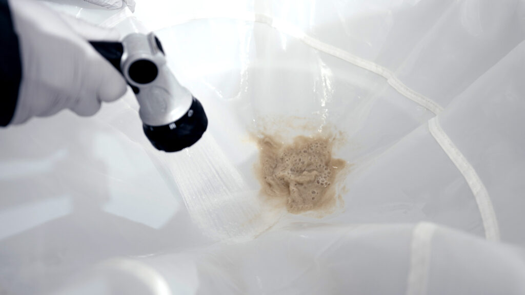 Cannabis trichomes being collected during ice water hash wash with bubble bags and spray nozzle.