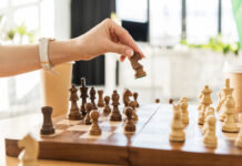 5 Essential Strategies from Leading Cannabis PR Agencies A hand moves a chess piece on a wooden chessboard, symbolizing strategic planning in cannabis public relations and earned media.