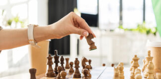 5 Essential Strategies from Leading Cannabis PR Agencies A hand moves a chess piece on a wooden chessboard, symbolizing strategic planning in cannabis public relations and earned media.