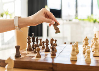 5 Essential Strategies from Leading Cannabis PR Agencies A hand moves a chess piece on a wooden chessboard, symbolizing strategic planning in cannabis public relations and earned media.