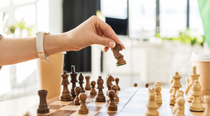 5 Essential Strategies from Leading Cannabis PR Agencies A hand moves a chess piece on a wooden chessboard, symbolizing strategic planning in cannabis public relations and earned media.