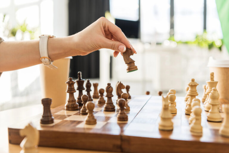 A hand moves a chess piece on a wooden chessboard, symbolizing strategic planning in cannabis public relations and earned media.