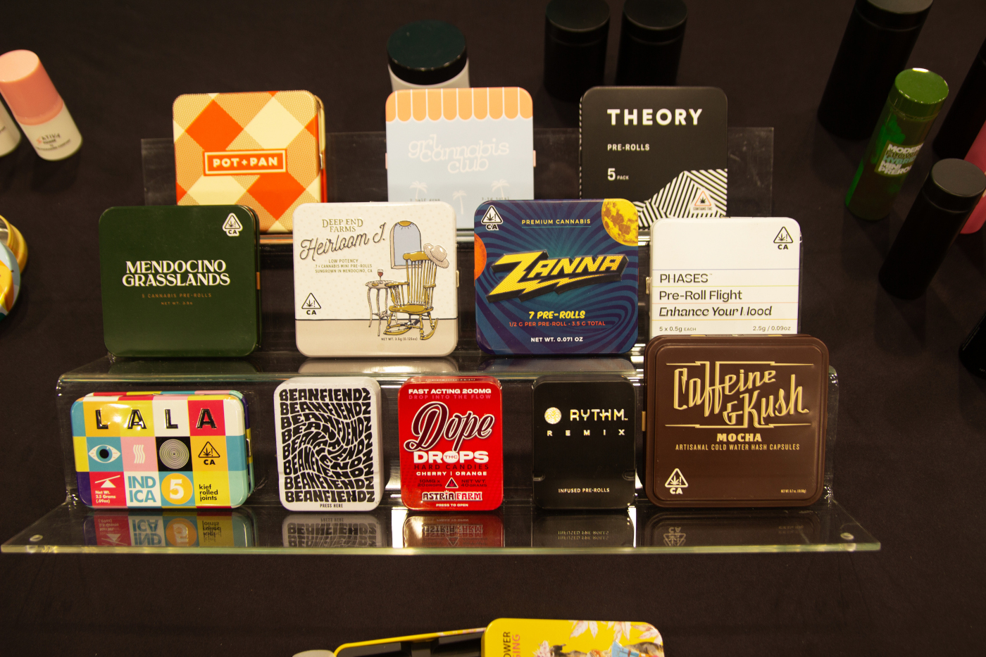 Collection of branded cannabis pre-roll tins from various companies displayed at MJBizCon 2025.