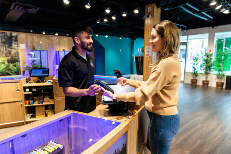 A budtender assists a customer with a purchase at a cannabis dispensary.