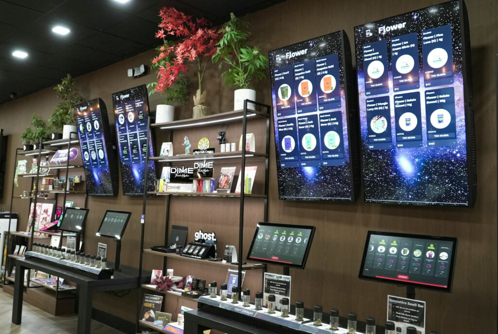 A modern cannabis dispensary interior featuring large digital menu screens and interactive displays, reflecting the digital-first retail experience shaping cannabis shopping in 2026.