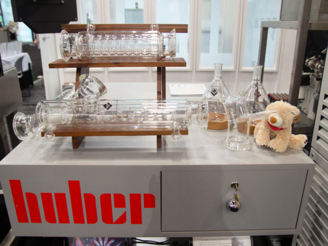 Huber booth at MJBizCon 2025 featuring scientific glassware and lab equipment for cannabis extraction.