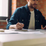 Pisgah Peaks Ventures on Building Marketing Teams That Scale Marketing consultant taking notes while reviewing strategy on a laptop in a light, modern workspace.