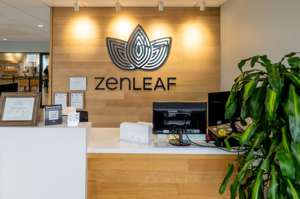 Zen Leaf dispensary reception area with wood feature wall, large Zen Leaf logo, and front desk.