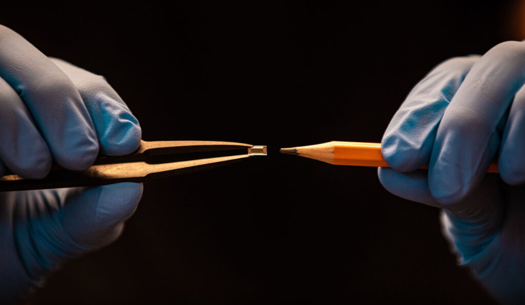 Close-up of a small Greentank Quantum Chip next to the tip of a pencil, showing the miniature scale of the heating platform.